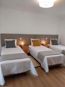 法蒂玛Casa com ALma的配有白色墙壁和木地板的客房内的两张床