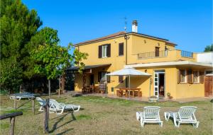 阿布鲁齐的罗塞托Amazing Home In Roseto Degli Abruzzi With Kitchen的黄色的房子,配有白色的椅子和雨伞