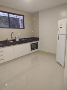 若昂佩索阿Lindo apto praia do bessa的厨房配有白色橱柜和白色冰箱。