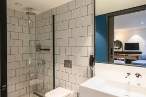 奥斯特韦克NEO KVL Hotel by TASIGO的浴室配有盥洗盆和带镜子的淋浴
