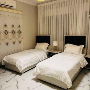 亚喀巴Luxury 4-bedrooms apartment的卧室内的两张床,配有白色床单和枕头