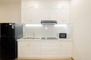 归仁TMS Apartment View Biển Luxury Quy Nhơn的厨房配有白色橱柜和黑色冰箱。