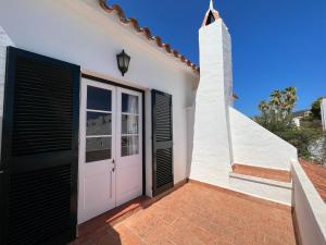 福尔内利斯MISTRAL 10 by SOM Menorca的白色的房子,有粉红色的门和黑色百叶窗