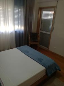 蒙蒂茹Apartamento da Aldeia的一间卧室设有一张床、一个窗口和一把椅子