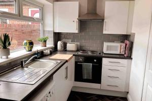 桑德兰Sunderland 2 bed easy access to whole city的厨房配有白色橱柜、水槽和微波炉