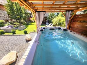 勒布罗伊斯Cosy Lodge au pied de l'Alpe D'Huez SKi et Détente Jacuzzi Piscine Sauna Bar Billard的后院的游泳池,带凉棚