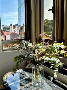 里瓦德塞利亚Apartamento - Riba De Sella的花瓶坐在窗前的桌子上