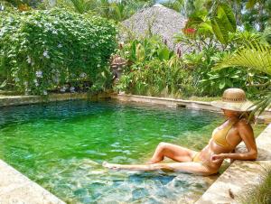 拉斯特拉纳斯Dream Glamping Jungle Bohio的坐在游泳池的戴帽子的女人