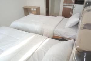 ParitOYO 93088 Celine Home Syariah的配有白色床单的酒店客房内的两张床
