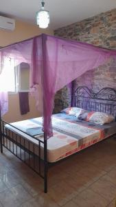 恩加帕鲁Chez Andre的一张带紫色天篷的床