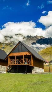 卡兹贝吉Cliffside cottage Kazbegi的一座大型的木制建筑,以群山为背景