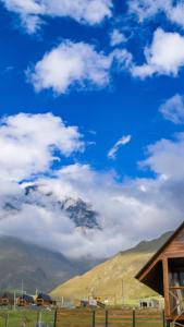 卡兹贝吉Cliffside cottage Kazbegi的享有蓝天和云的山景