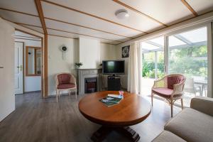 奥斯特韦克26, gelegen in het bosrijke Oisterwijk met privé tuin!的客厅配有桌椅和电视。