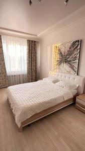 卡拉甘达Luxe Appartments on Stepnoy的卧室配有一张白色大床,墙上挂有绘画作品