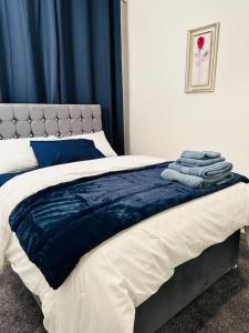 德比Bespoke 2 Bedroom Apt Derby City的一张带蓝色和白色床单及毛巾的床