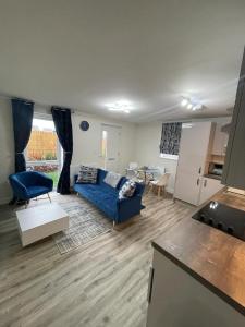 米尔顿凯恩斯Luxurious Apartment in Brooklands的一间带蓝色沙发的客厅和一间厨房