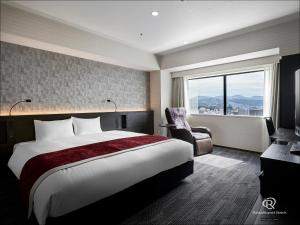 广岛Daiwa Roynet Hotel Hiroshima-ekimae的卧室配有床、椅子和窗户。