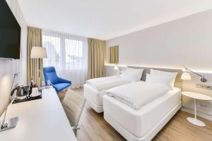 魏因海姆魏英海姆NH酒店的酒店客房配有白色的床和蓝色椅子
