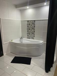 沃伦塔里Karra Hotels的浴室设有白色浴缸及黑色淋浴