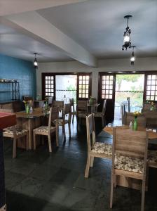 里奥迪孔塔斯Pousada A Pérola的餐厅设有木桌、椅子和窗户。