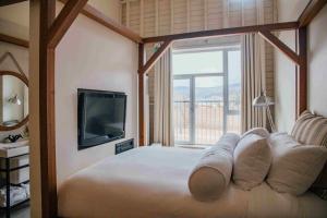 拜圣保罗勒热曼夏荷乐瓦Spa酒店的一间卧室设有一张带电视和窗户的床。