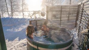 罗瓦涅米Lysti Cottage by the lake and magical countryside的两人在雪地的热水浴缸中