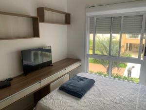 弗洛里亚诺波利斯Apartamento na Praia do Campeche的一间卧室设有一张床、一台电视和一个窗口。