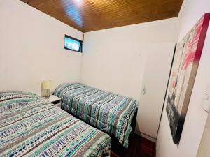 塔尔卡Casa y departamentos amoblados Talca的一间卧室设有两张床,墙上配有电视。