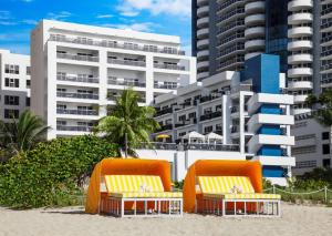 迈阿密海滩Hilton Cabana Miami Beach Resort的大楼前的海滩上配有2把躺椅