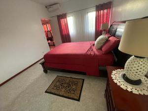 普拉亚Isa House - Private Rooms in a Shared Duplex的一间卧室配有红色的床和一张带台灯的桌子