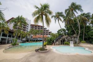 山打根沙巴大酒店的一个带游泳池和棕榈树的度假村
