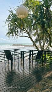 乌纳瓦图纳Elysium的海滩旁木板路上的一张桌子和两把椅子