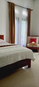 纳闽巴霍Inang Amang Homestay的卧室配有床、椅子和窗户。