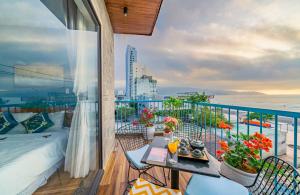 岘港卡尼海滨公寓式酒店的阳台配有床和桌子。