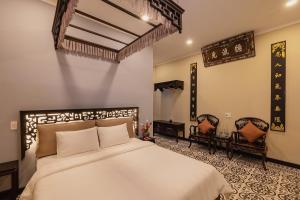 顺化HueNam Residence的一间卧室配有一张大床和两把椅子