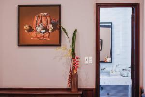顺化HueNam Residence的浴室墙上挂着照片,配有花瓶