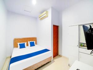棉兰Sg Premium Guest House By Helocus的一间卧室配有一张带蓝色枕头的床和一台电视。