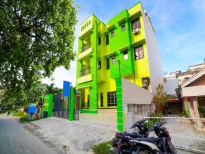 棉兰Sg Premium Guest House By Helocus的一座绿色和黄色的建筑,前面停有摩托车