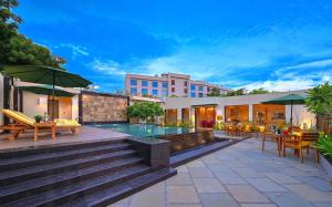阿格拉Royale Sarovar Portico Agra的一个带游泳池和桌椅的度假酒店
