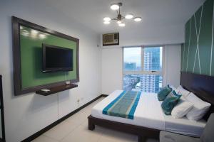 马尼拉Millenia Suites Cozy Studio Unit 3003的一间卧室设有一张带平面电视的床。