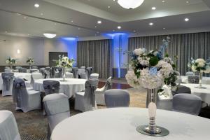 沃尔瑟姆阿比Delta Hotels by Marriott Waltham Abbey的宴会厅配有白色的桌椅和鲜花