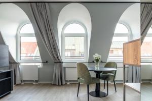 慕尼黑numa I Blend Apartments的用餐室设有拱形窗户和桌椅