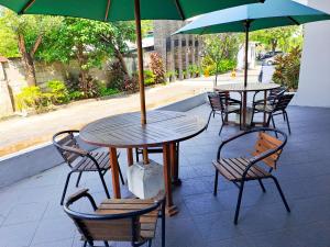 DaresHOTEL TILAMAS的庭院里配有两张桌子和椅子以及遮阳伞