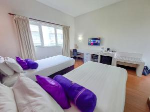 DaresHOTEL TILAMAS的酒店客房配有两张带紫色枕头的床