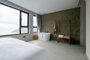 舟山听涧·登观海景Villa设计师酒店的一间带浴缸和大窗户的卧室