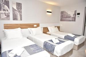 巴统Old Batumi Hotel的酒店客房设有三张床,墙上挂有绘画作品