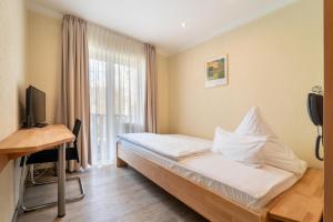 宁布雷希特比热巴赫尔酒店的一间卧室配有一张床、一张书桌和一个窗户。