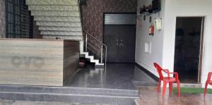 勒克瑙OYO Flagship Tirupati Lawn And Hotel的一间设有两张红色椅子的房间和楼梯