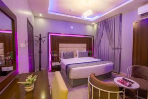 达曼Swat Hotel Apartments的紫色卧室配有一张床和一张沙发