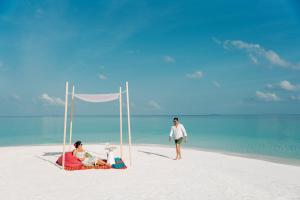 丹格迪Nova Maldives的坐在海滩上的男人和女人